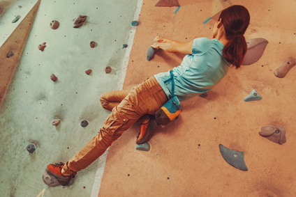 Free climber young woman climbing artificial boulder indoor. Focus on hands